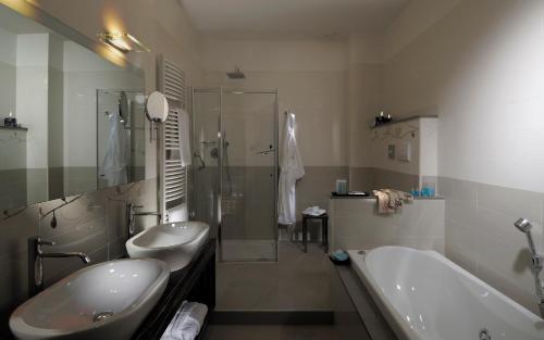 a bathroom with two sinks and a tub and a shower at Hotel La Cartiera in Vignola