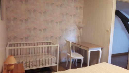 a room with a crib and a table and a desk at Gîte Le Moulin de la Chaussee in Saint-Denis-dʼOrques
