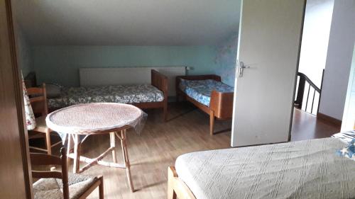 a room with two beds and a table and chairs at Gîte Le Moulin de la Chaussee in Saint-Denis-dʼOrques
