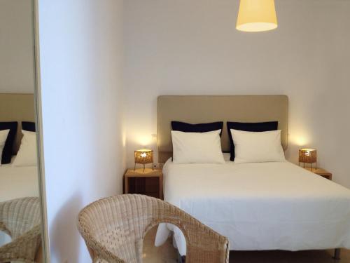 une chambre avec un lit blanc et un miroir dans l'établissement Apartamentos Doña Carmen, à Malaga