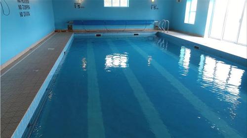 a swimming pool with blue water in a building at Quilty Holiday Cottages - Type A in Quilty