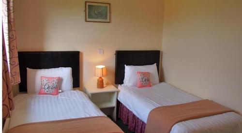 a room with two beds and a table with a lamp at Quilty Holiday Cottages - Type A in Quilty