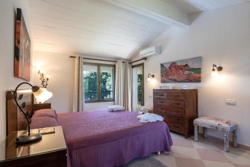 ein Schlafzimmer mit einem lila Bett, einer Kommode und einem Fenster in der Unterkunft Villa Can Llamas in Pollença