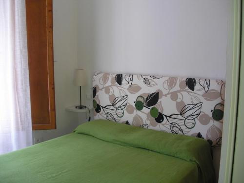 a bedroom with a green bed with a floral headboard at Residence I Pini in Capoliveri