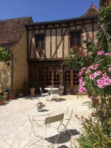 een terras met een tafel en stoelen voor een gebouw bij La Ferme de l'Embellie Gîtes et Chambres d'Hôtes in Le Buisson de Cadouin
