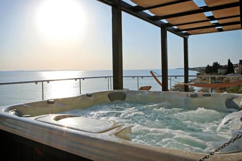 a jacuzzi tub on a deck with the ocean at Hotel Delfin in Zadar