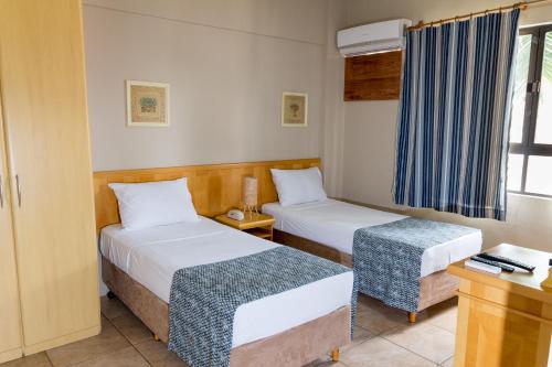 a hotel room with two beds and a window at Maria Quitéria Hotel & Flat in Feira de Santana