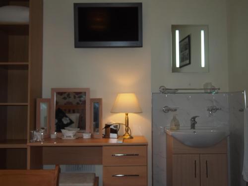 bagno con lavandino e scrivania con lampada di Bodhyfryd Guesthouse a Betws-y-coed