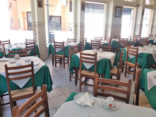 een eetkamer met tafels en stoelen met groene servetten bij Hotel Alianca in Figueira da Foz