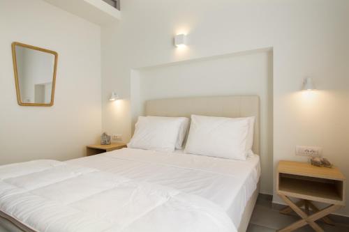 a bedroom with a large white bed with a mirror at Vourkari Village in Vourkarion