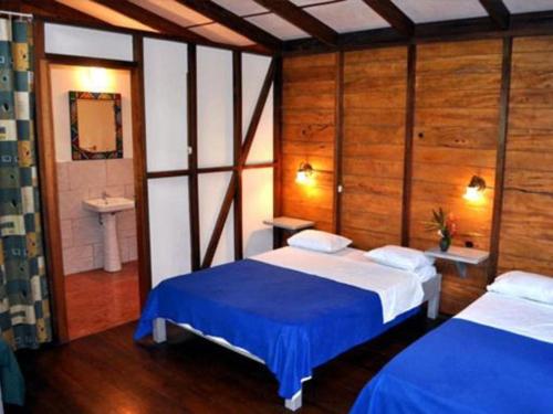 a bedroom with two beds and a bathroom with a sink at El Tucan Jungle Lodge in Puerto Viejo