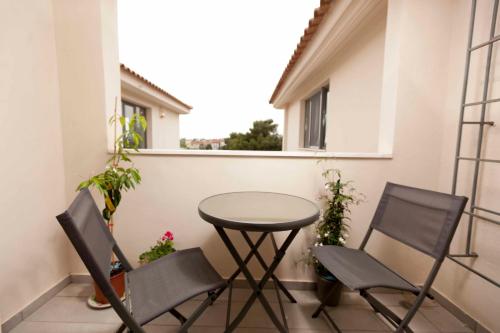 a small table and two chairs on a balcony at CHROMA Lodge Pikermi in Pikérmion