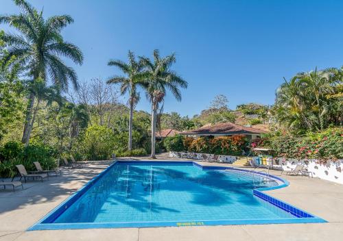 a swimming pool in a resort with palm trees at Hotel Colinas del Sol in Atenas