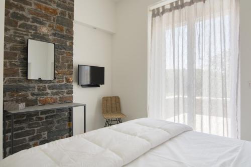 a bedroom with a brick wall and a bed and a window at Vourkari Village in Vourkarion
