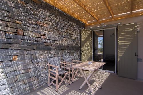 a patio with two chairs and a table and a stone wall at Vourkari Village in Vourkarion