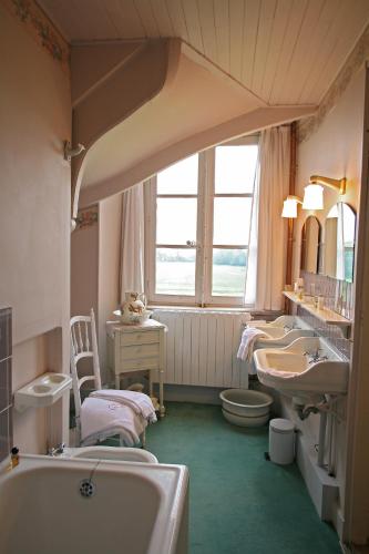 une salle de bain avec deux lavabos et une baignoire et des toilettes dans l'établissement Château de Beaujeu, à Sens-Beaujeu