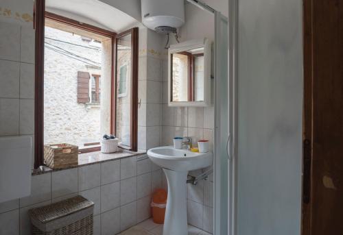 a white bathroom with a sink and a window at Holiday Home Vizinada in Vižinada