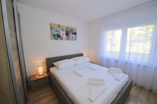 a bedroom with a bed with white sheets and a window at Villa Martina in Ika