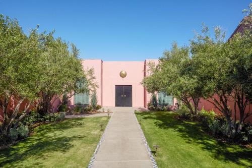 a pink building with a black door and trees at Sands Hotel and Spa in Indian Wells