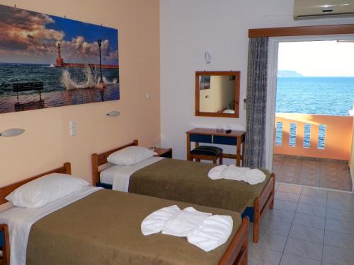 two beds in a room with a view of the ocean at Christi Apartments in Kalyves