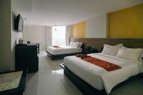 a hotel room with two beds and a television at Hotel El Español Paseo de Montejo in Mérida