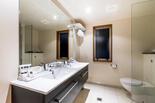 a bathroom with two sinks and a toilet at Distinction Te Anau Hotel & Villas in Te Anau