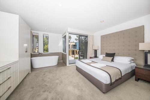 1 dormitorio con 1 cama grande y bañera en The Sebel Creswick Forest Resort, en Creswick