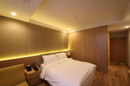 una camera da letto con un grande letto bianco e armadi di Benikea The H Hotel a Hwaseong