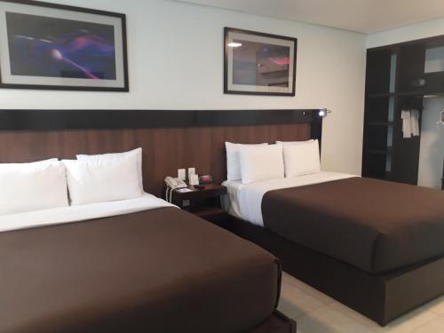 a hotel room with two beds and a tv at Hotel & Suites PF in Mexico City
