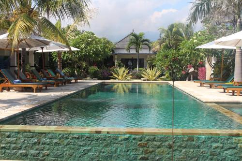 a swimming pool with chairs and a resort at Kelapa Lovina Beach Villa in Lovina