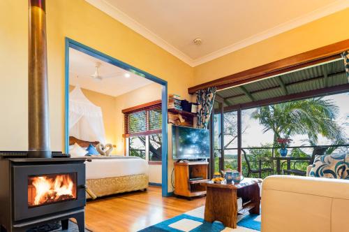a living room with a fireplace and a bed and a bedroom at Lillypilly's Cottages & Day Spa in Maleny