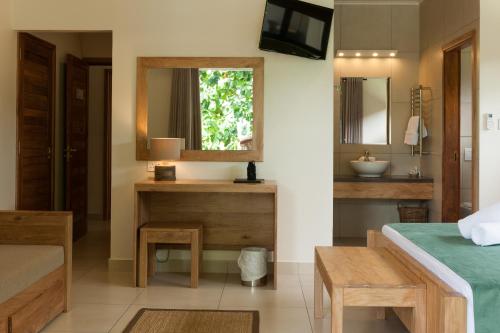 a hotel room with a bed, table and a mirror at Le Repaire - Boutique Hotel & Restaurant in La Digue