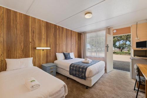 two beds in a room with wooden walls at Benalla Tourist Park in Benalla