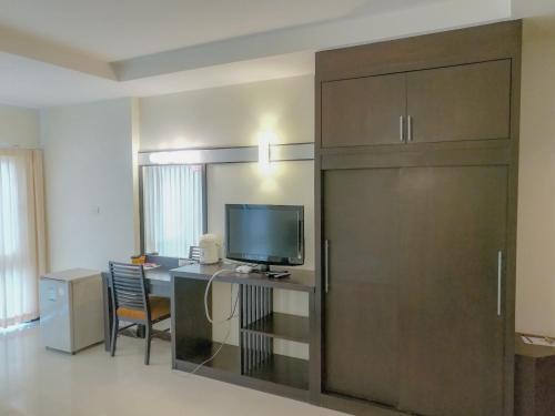 Zimmer mit einem Schreibtisch, einem TV und einer Schiebetür in der Unterkunft K.M. House in Krabi