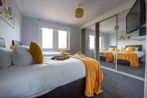 una camera d'albergo con due letti e una televisione di PREMIER - Motherwell Apartment a Carfin