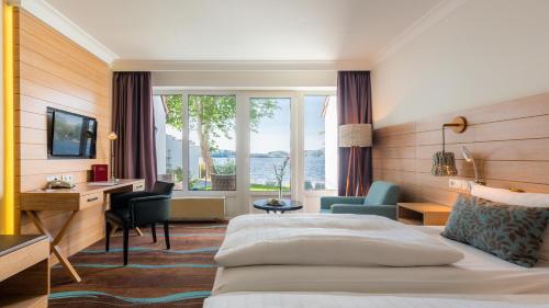 a hotel room with a bed and a desk and a window at Hotel Der Seehof in Ratzeburg