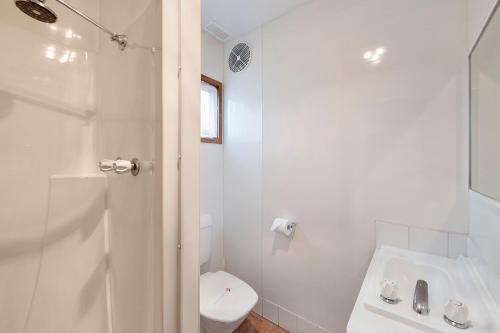 a white bathroom with a toilet and a sink at Benalla Tourist Park in Benalla