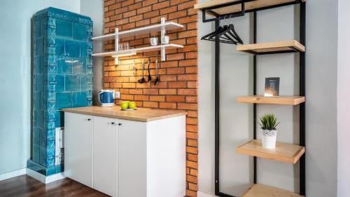 a kitchen with white cabinets and a brick wall at Flamingo Premium Hostel in Krakow