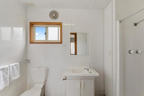 a white bathroom with a toilet and a sink at Benalla Tourist Park in Benalla