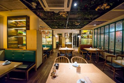 een eetkamer met tafels en stoelen in een restaurant bij MG Hotel (青岛民国酒店) in Qingdao