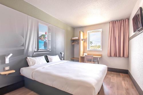 コダンにあるB&B HOTEL Lorient Caudanの大きなベッドとテーブルが備わるホテルルームです。