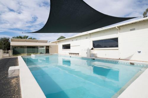a swimming pool with a swimming pool umbrella at Benalla Tourist Park in Benalla