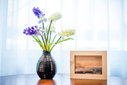 a vase with purple and white flowers next to a picture at MG Hotel St Michael's Cathedral, Qingdao in Qingdao