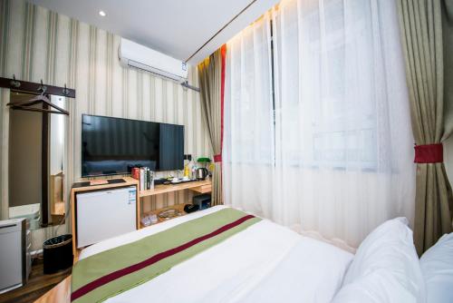 a hotel room with a bed and a television at MG Hotel St Michael's Cathedral, Qingdao in Qingdao