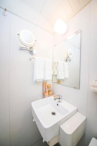 a white bathroom with a sink and a mirror at MG Hotel St Michael's Cathedral, Qingdao in Qingdao