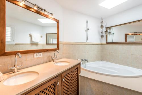 Un baño con dos lavabos, una bañera y un espejo. en Villa Orquidea - Amazing landscape view, en Santa Eulària des Riu