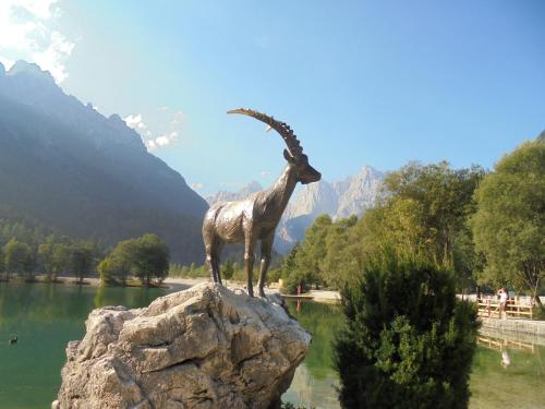 a statue of a goat on a rock near a lake at Apartment Jakelj in Kranjska Gora