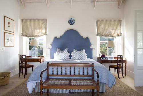 a bedroom with a large bed with a blue headboard at La Cotte Orchard Cottages in Franschhoek