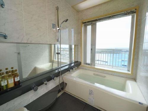 a bathroom with a bath tub and a window at Hotel East China Sea in Ishigaki Island