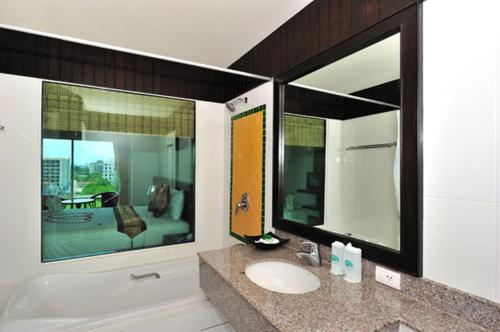 a bathroom with two mirrors and a sink and a tub at APK Resort in Patong Beach